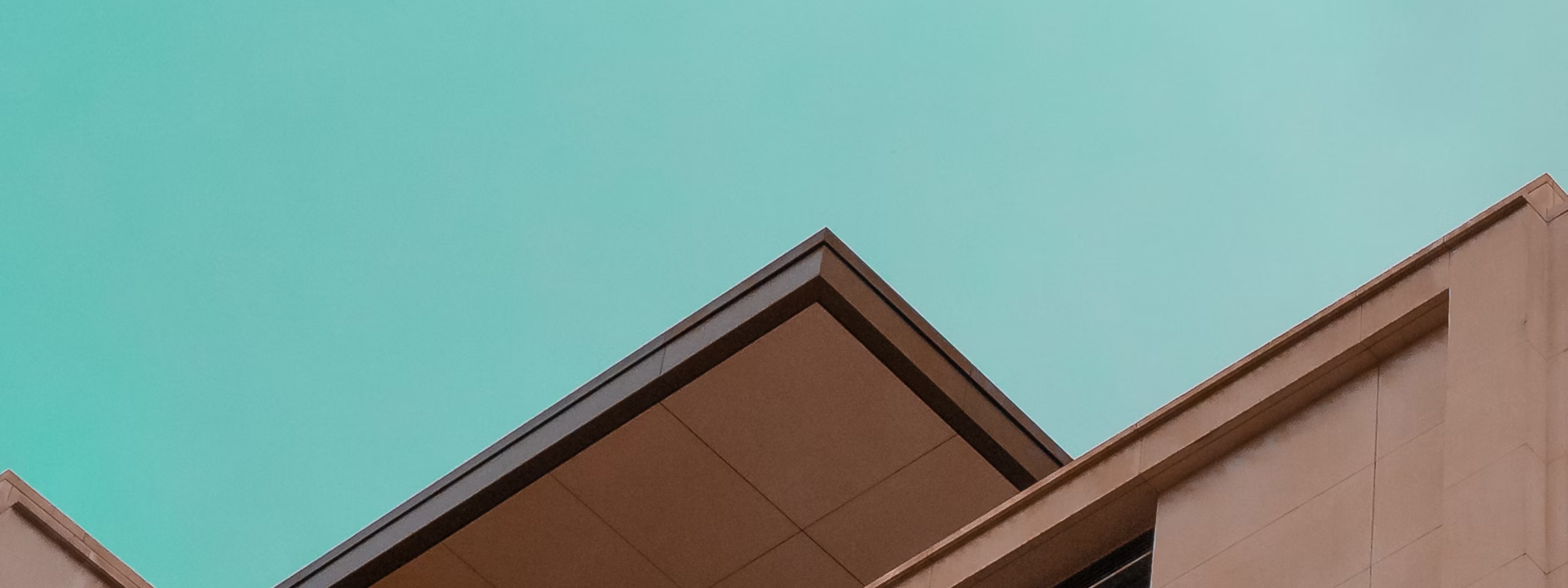 Modern building rooftops against clear turquoise sky with geometric angles
