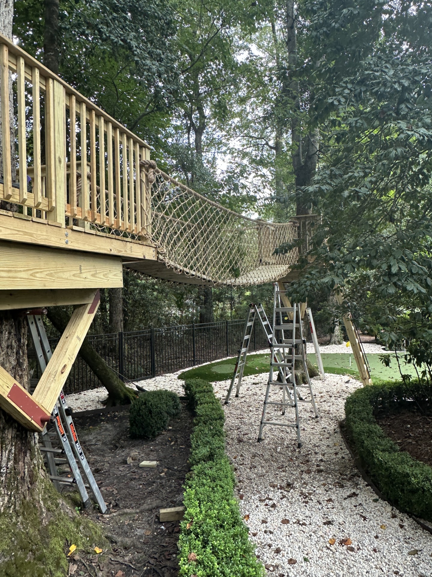 Elevated treehouse deck joined to a second platform by a rope suspension bridge