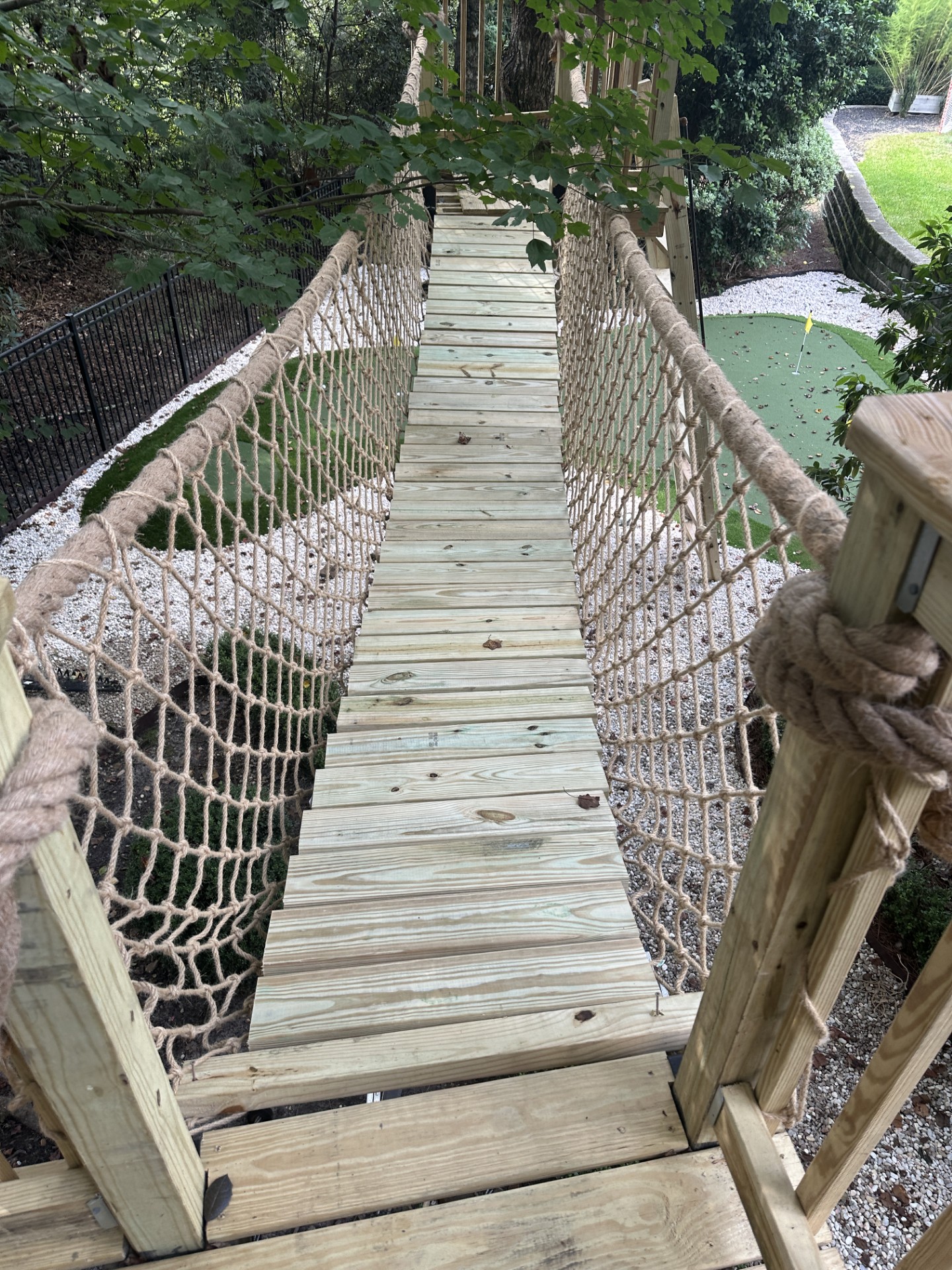 Looking along the plank and rope suspension bridge between two treehouse platforms