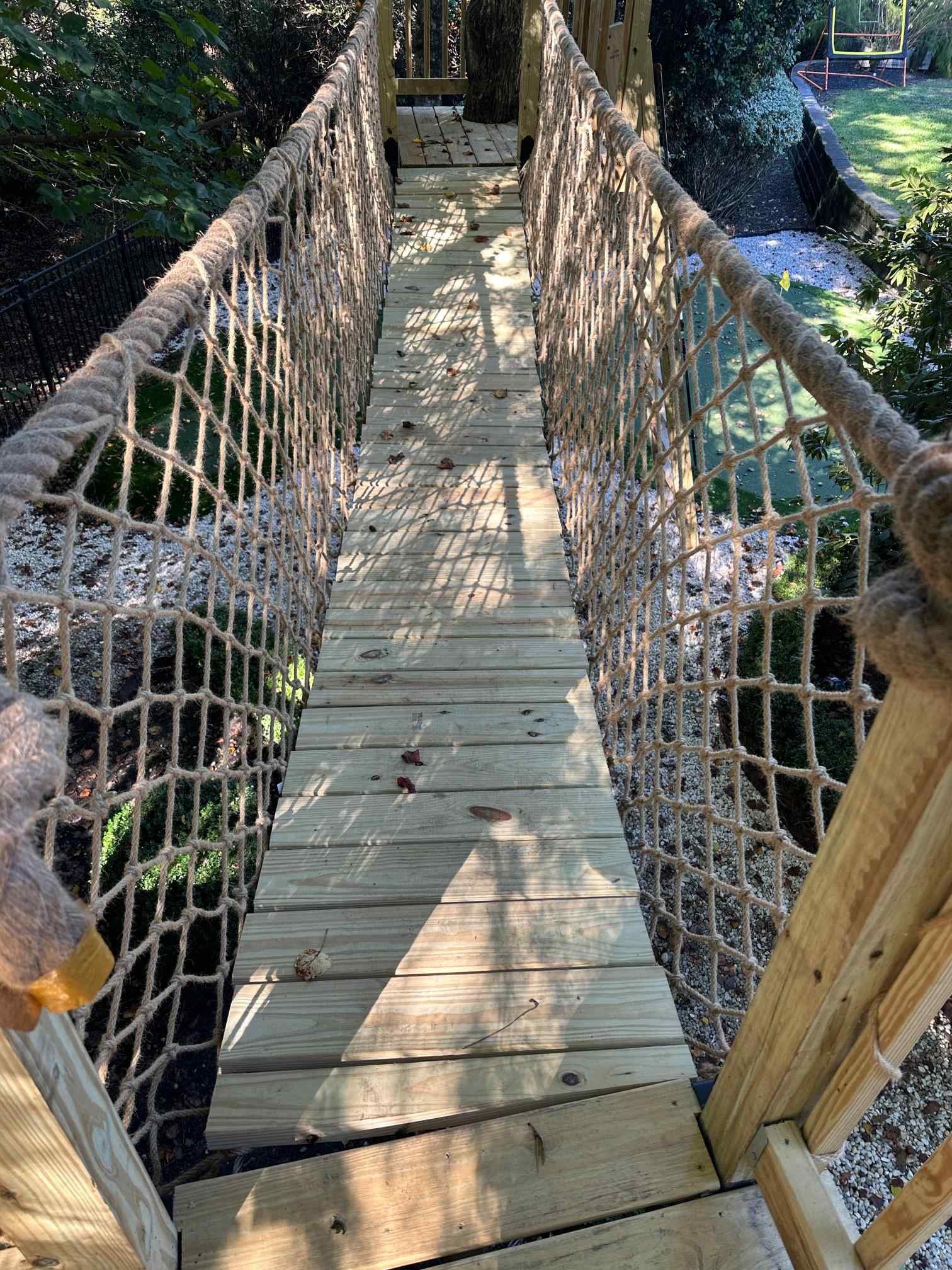 Looking along the plank and rope suspension bridge between two treehouse platforms
